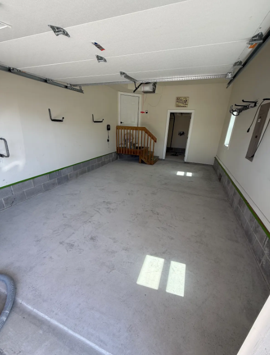 Bare gray concrete garage floor prepped with edge tape before a flake floor coating