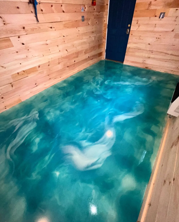 Swirling teal and white metallic epoxy floor in a pine-paneled commercial room with a navy blue door