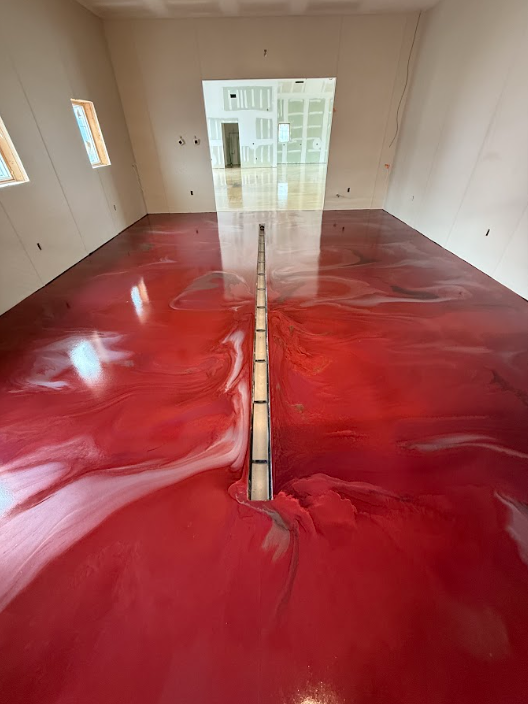 Red metallic epoxy floor with stainless trench drain in an industrial facility