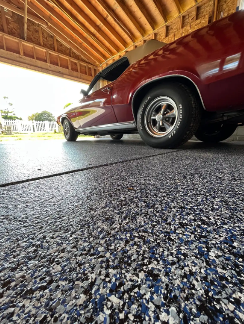 Low-angle view of a blue, white, and black flake garage floor with a maroon classic car parked on it