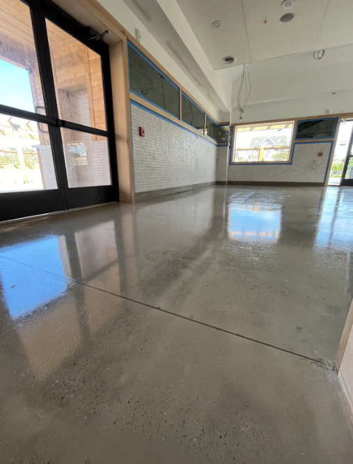 High-gloss polished concrete floor in a bright commercial storefront with glass doors
