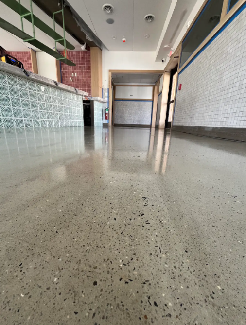 Polished concrete floor running down a deli and market hallway past a tiled service counter