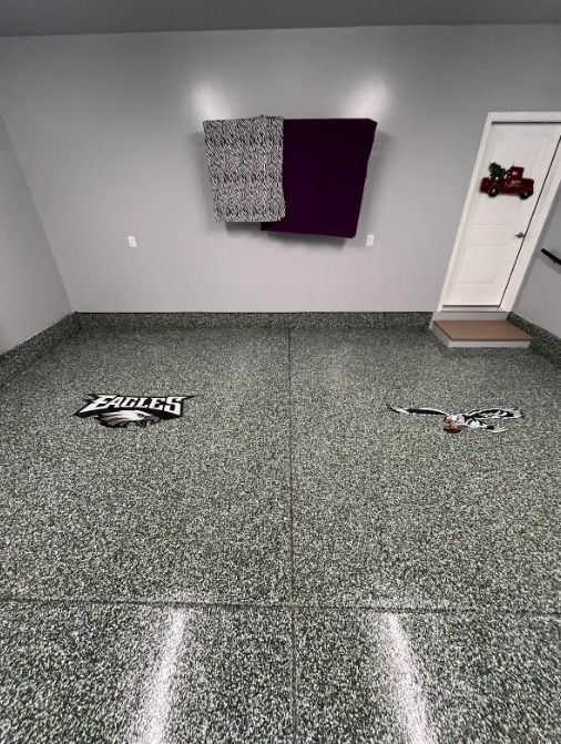 Gray and black flake floor with custom Philadelphia Eagles logo inlays in a finished room