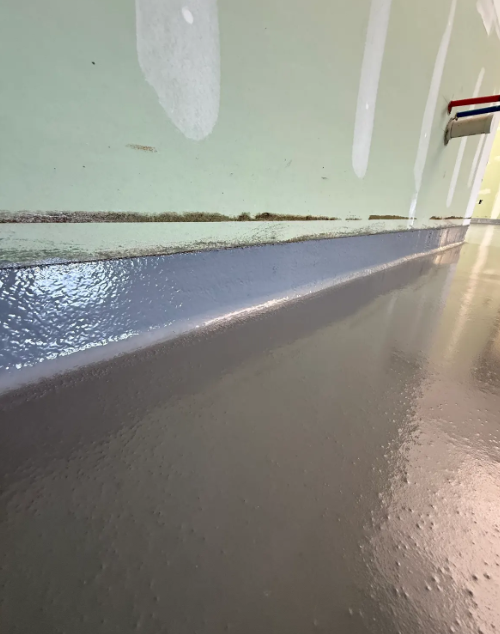 Close-up of a seamless gray epoxy floor with an integral cove base up the wall
