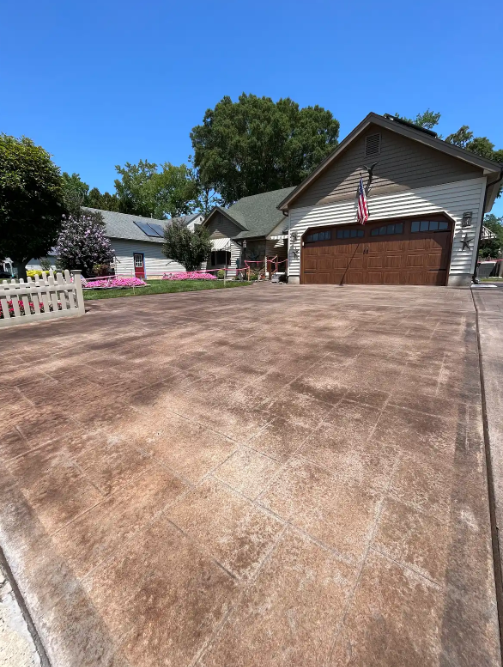 Stamped and stained decorative concrete driveway in front of a home flying an American flag