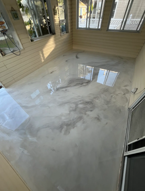 Glossy white and gray metallic epoxy floor in a bright wood-paneled sunroom
