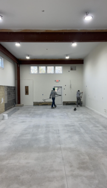 Surface Shield crew applying solid coating over the prepped concrete floor in the same room before completion