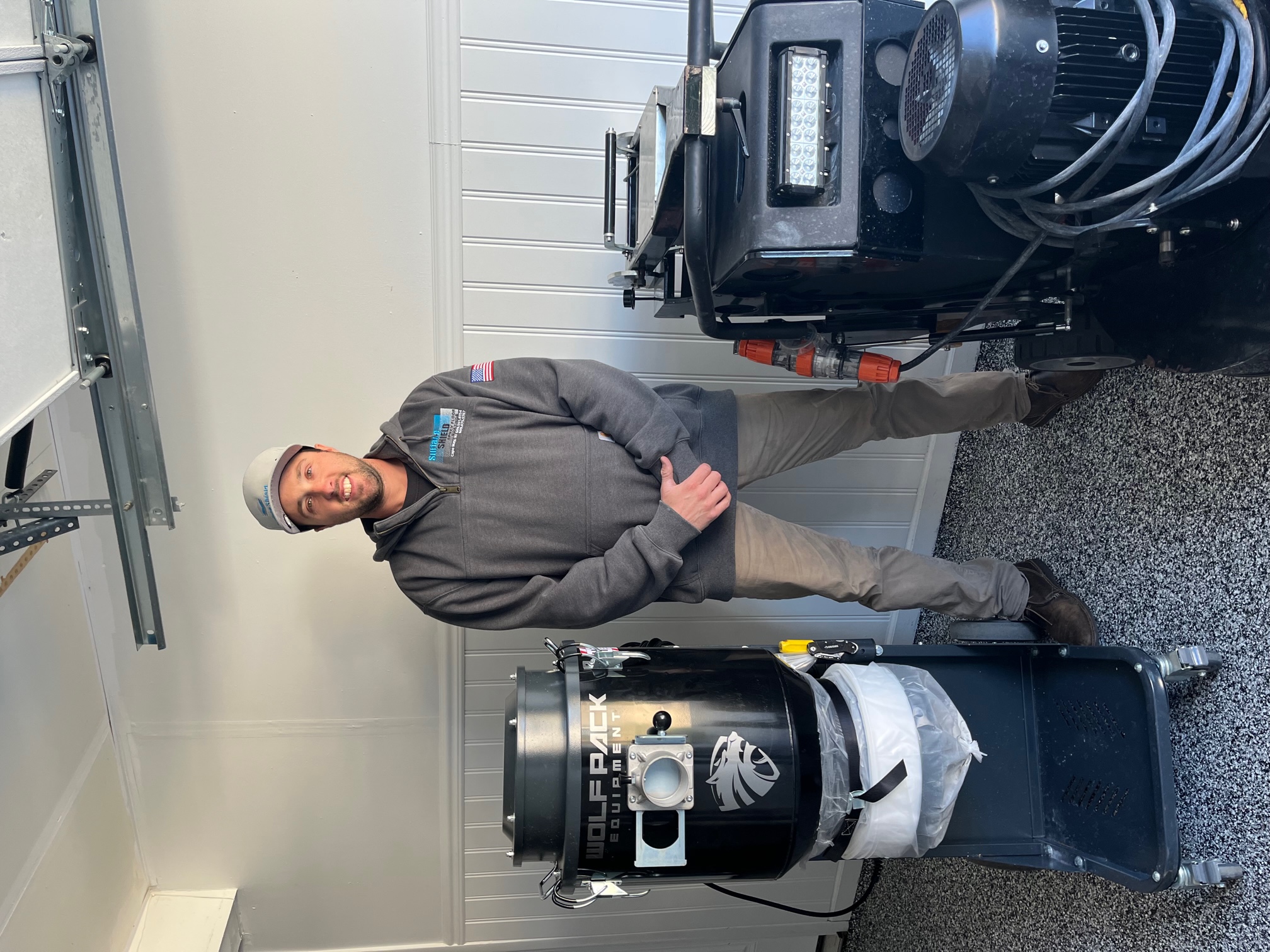 Surface Shield owner and operator standing with professional dust extraction and concrete grinding equipment